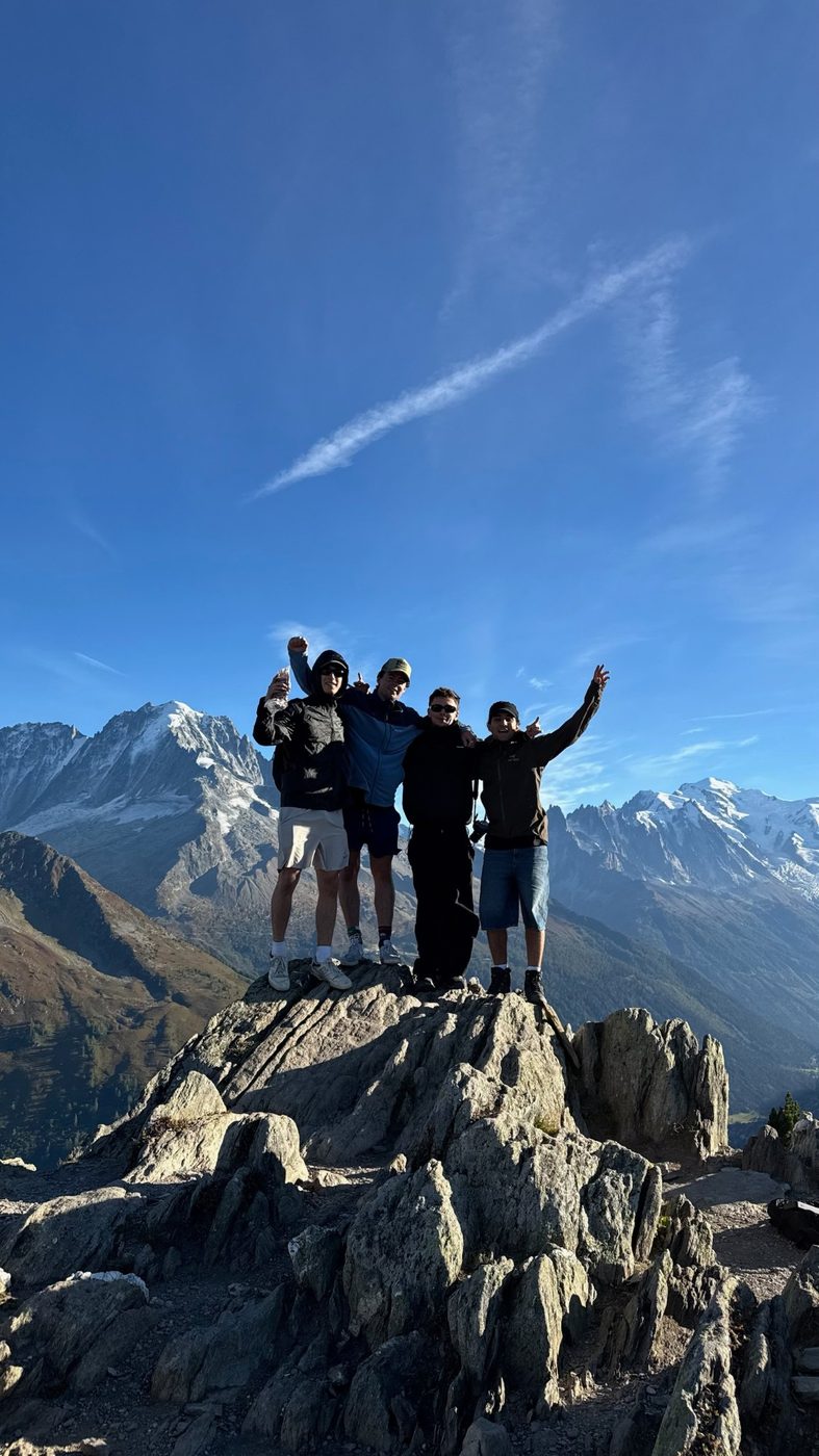 Four friends cheering on a rocky summit
